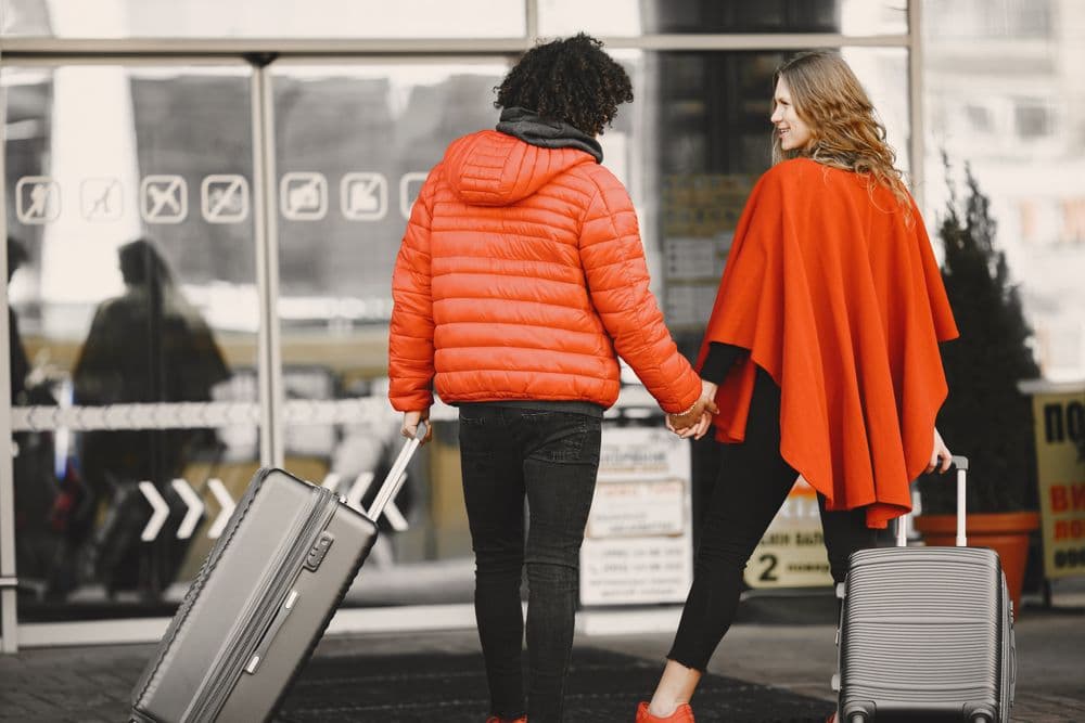 A couple with suitcases walking into an airport